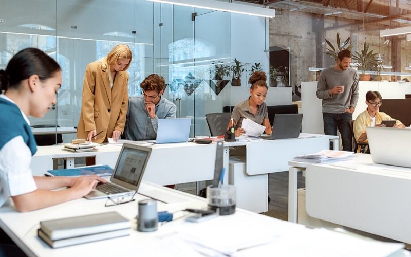 a group of business people working on lap tops in a white office with white tables