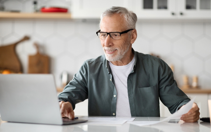 older man sitting at counter working on laptop
