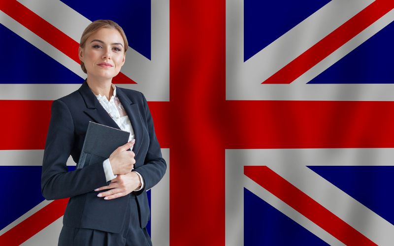 Woman smiling and holding a notebook with the national flag of the United Kingdom in the backdrop