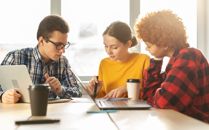 Three people working together with their laptops opened