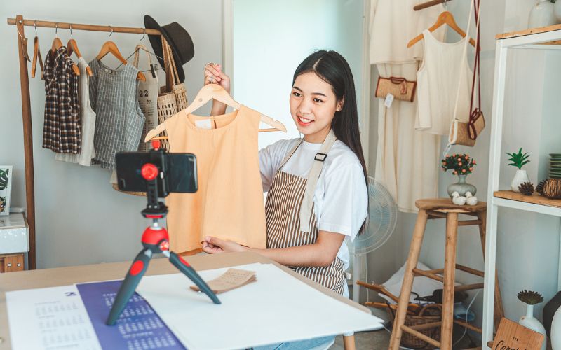 Girl smiling and taking photos of her clothing to sell