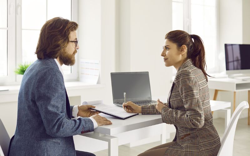 Man handing over a contract as the woman is signing it