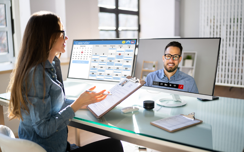 Women holding clipboard talking to man through video chat